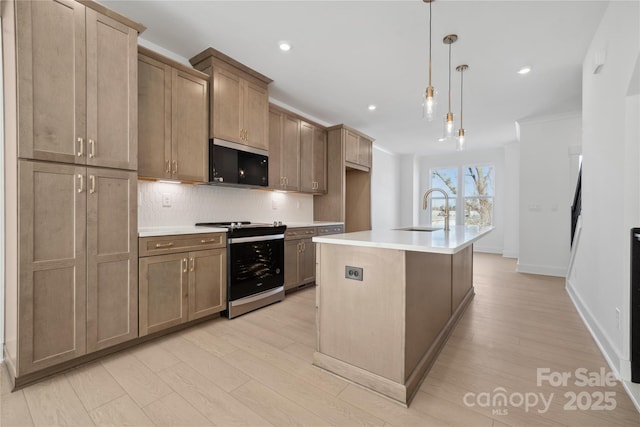 kitchen featuring light countertops, backsplash, a sink, range with electric cooktop, and black microwave