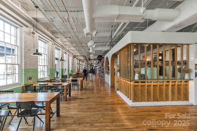 dining space featuring wood-type flooring and brick wall