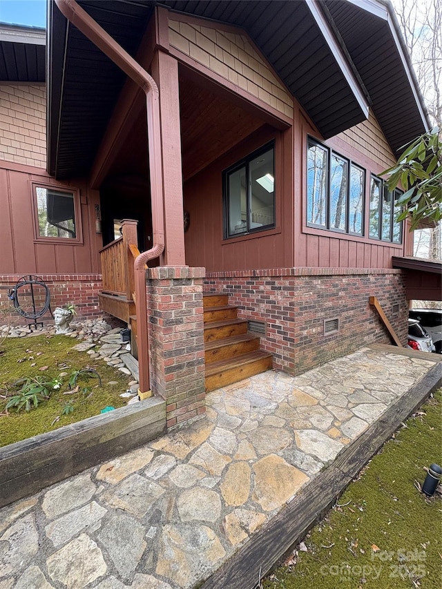 view of property exterior with brick siding, crawl space, and board and batten siding