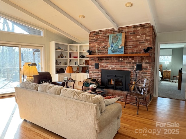 living area with lofted ceiling with beams, a fireplace, and wood finished floors