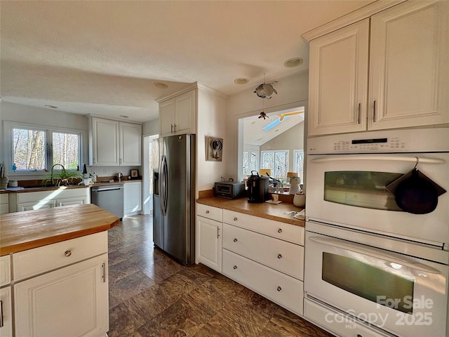 kitchen featuring white cabinets, wood counters, stainless steel appliances, and a sink