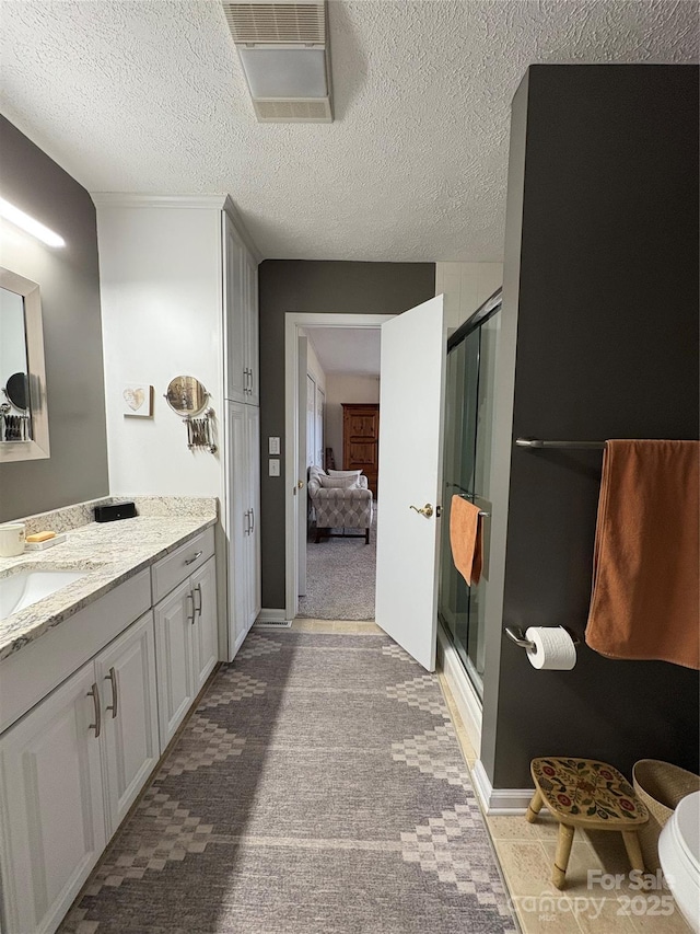 ensuite bathroom featuring a stall shower, visible vents, and a textured ceiling