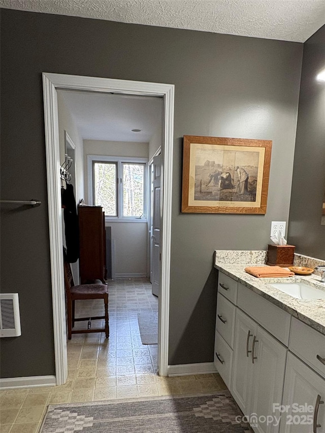 bathroom with vanity, baseboards, and a textured ceiling