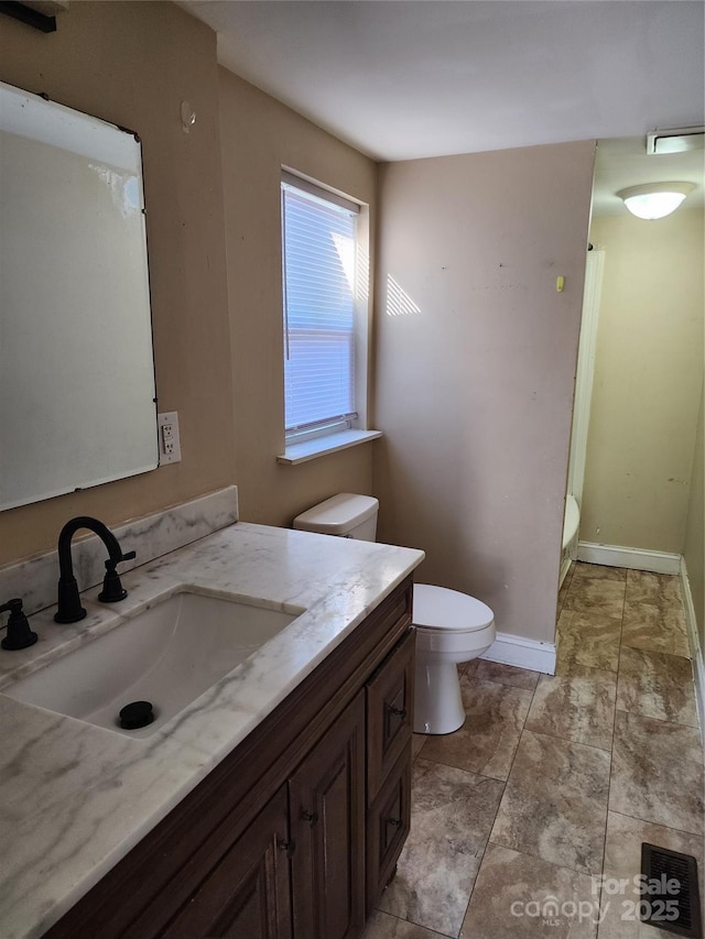 bathroom featuring a stall shower, vanity, toilet, and baseboards