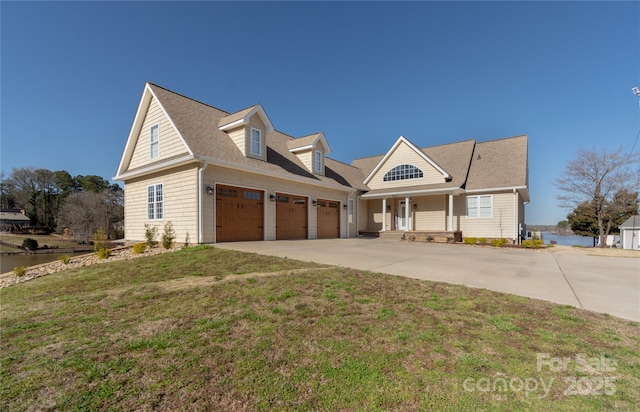 view of front of home featuring a water view, driveway, covered porch, roof with shingles, and a front yard