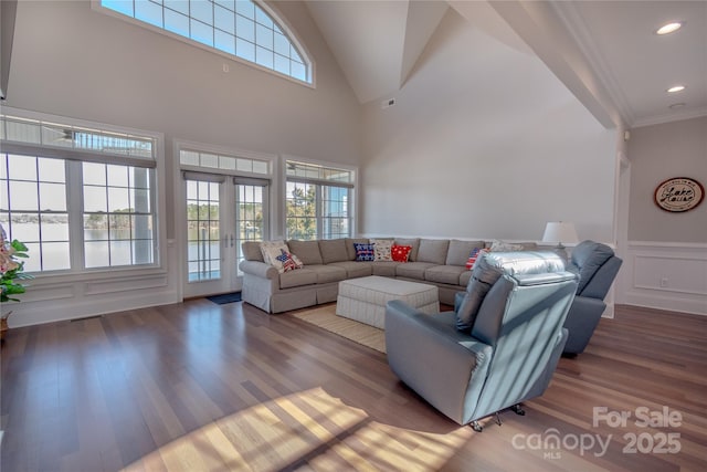 living area with a decorative wall, wood finished floors, a wealth of natural light, and ornamental molding