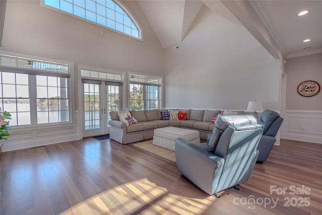 living area featuring wainscoting, a decorative wall, a healthy amount of sunlight, and wood finished floors