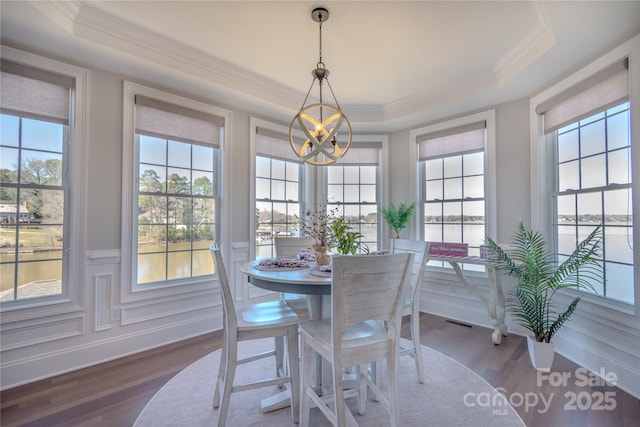 dining room with visible vents, a raised ceiling, an inviting chandelier, and wood finished floors