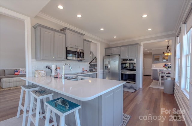 kitchen featuring a sink, a kitchen breakfast bar, appliances with stainless steel finishes, and gray cabinetry