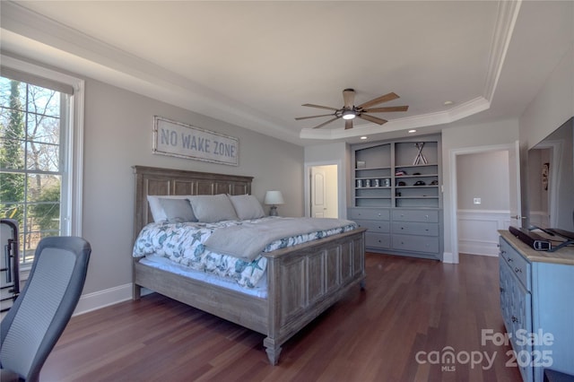 bedroom with dark wood finished floors, a tray ceiling, baseboards, and ceiling fan