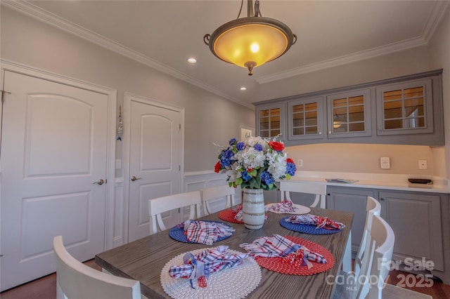 dining space featuring crown molding, a decorative wall, recessed lighting, and wainscoting