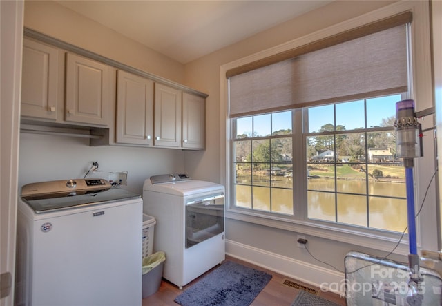 clothes washing area with a wealth of natural light, visible vents, cabinet space, and independent washer and dryer