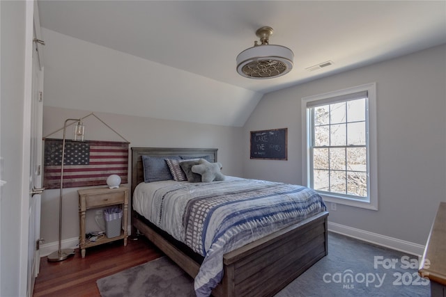 bedroom featuring visible vents, ceiling fan, baseboards, vaulted ceiling, and wood finished floors