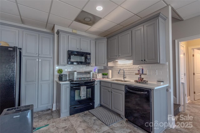 kitchen featuring black appliances, gray cabinetry, a sink, backsplash, and light countertops