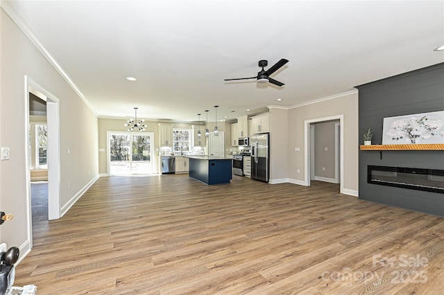 living room with ornamental molding, a large fireplace, light wood finished floors, and ceiling fan with notable chandelier