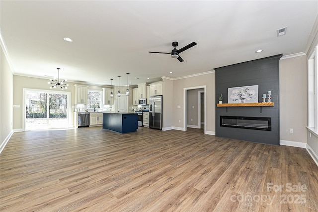 unfurnished living room with crown molding, light wood-style floors, visible vents, and a fireplace