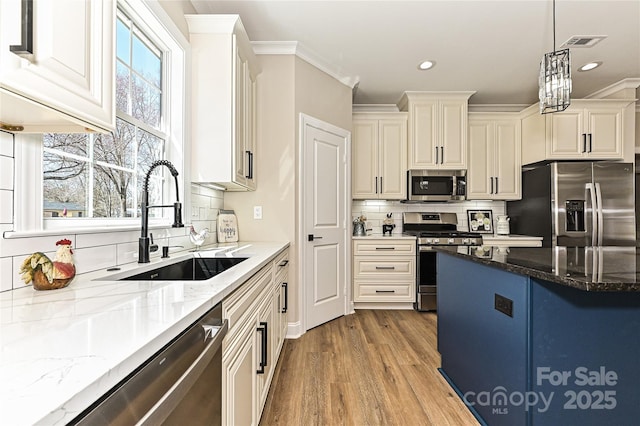 kitchen with light stone counters, stainless steel appliances, a sink, visible vents, and decorative backsplash