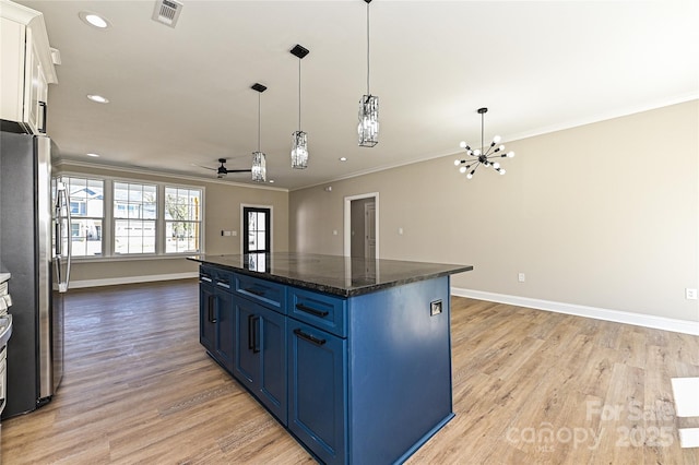 kitchen featuring light wood-style flooring, blue cabinets, visible vents, freestanding refrigerator, and crown molding