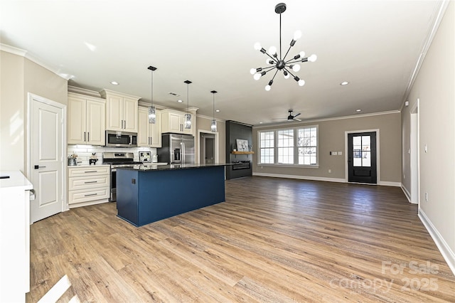 kitchen featuring ceiling fan with notable chandelier, a center island, appliances with stainless steel finishes, light wood-type flooring, and decorative backsplash