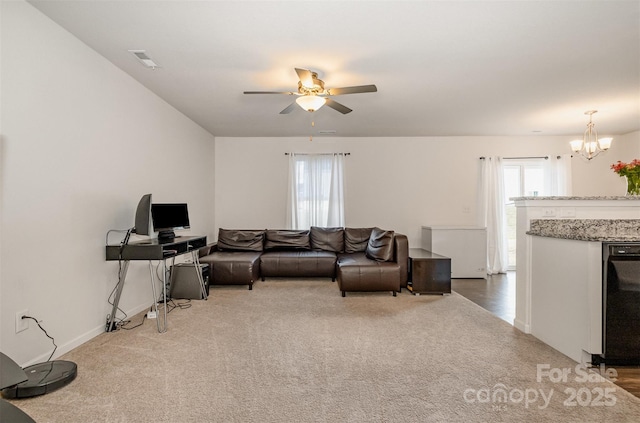 carpeted living area featuring visible vents, baseboards, and ceiling fan with notable chandelier