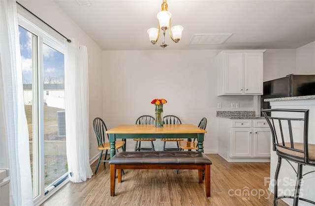 dining area with light wood-type flooring, baseboards, visible vents, and a notable chandelier