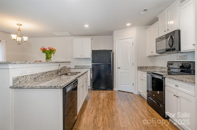 kitchen with white cabinetry, a sink, light wood-style flooring, and black appliances