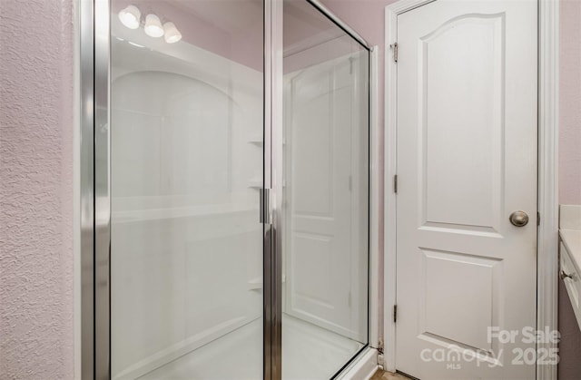 bathroom featuring a textured wall and a shower stall