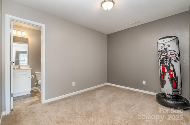 unfurnished bedroom with light carpet, visible vents, baseboards, connected bathroom, and a sink