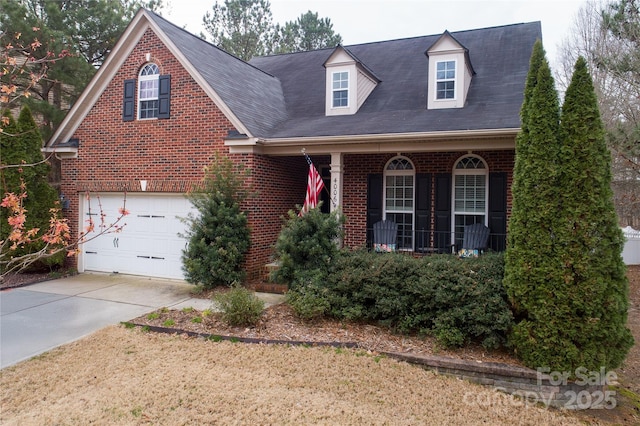 view of front of house with covered porch, brick siding, and driveway