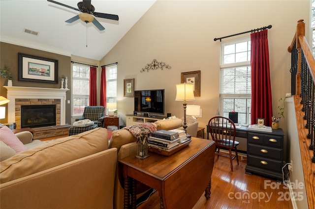 living room featuring a wealth of natural light, a stone fireplace, hardwood / wood-style floors, and visible vents