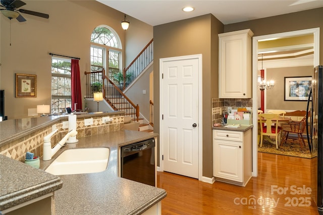 kitchen featuring tasteful backsplash, light wood-style floors, white cabinetry, a sink, and dishwasher