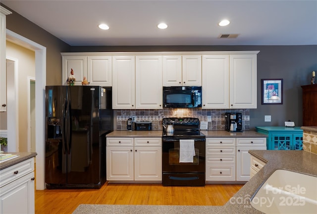 kitchen featuring light wood finished floors, tasteful backsplash, visible vents, white cabinets, and black appliances