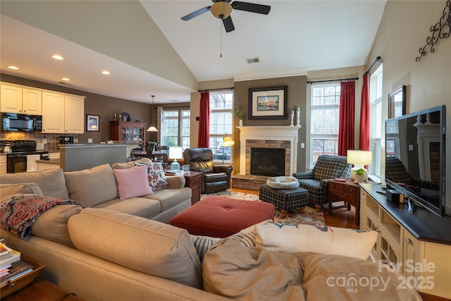 living area with a fireplace, recessed lighting, visible vents, ceiling fan, and wood finished floors