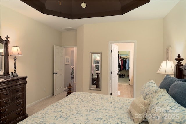 bedroom with light colored carpet, baseboards, a spacious closet, a closet, and a tray ceiling