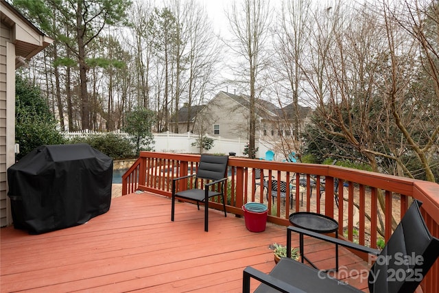 wooden deck with grilling area and a fenced backyard