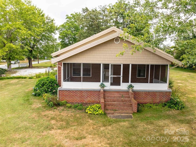 rear view of house featuring a sunroom, stairway, a lawn, and brick siding