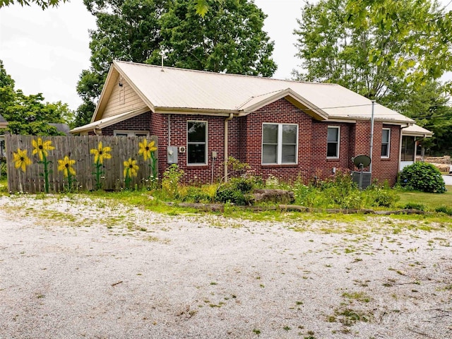 view of front of house featuring metal roof, brick siding, and fence