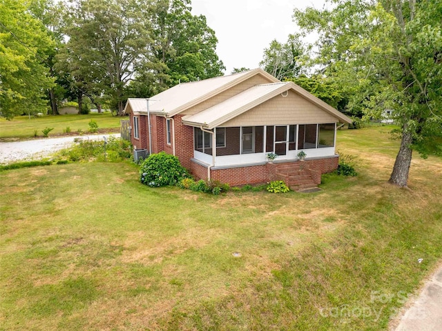 view of property exterior with a sunroom, central AC unit, a lawn, and brick siding