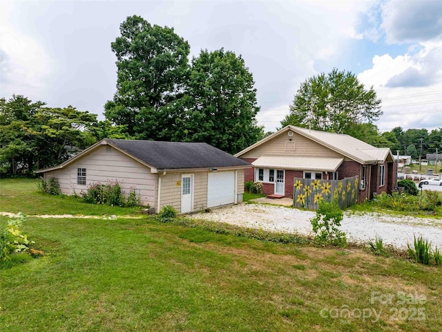 view of front of property with driveway, brick siding, a front yard, and a detached garage