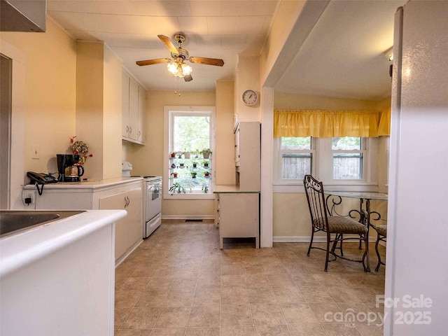 kitchen with light countertops, electric range, a ceiling fan, white cabinetry, and baseboards