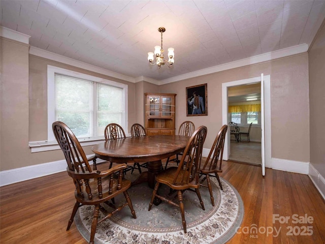 dining area with crown molding, a notable chandelier, baseboards, and wood finished floors