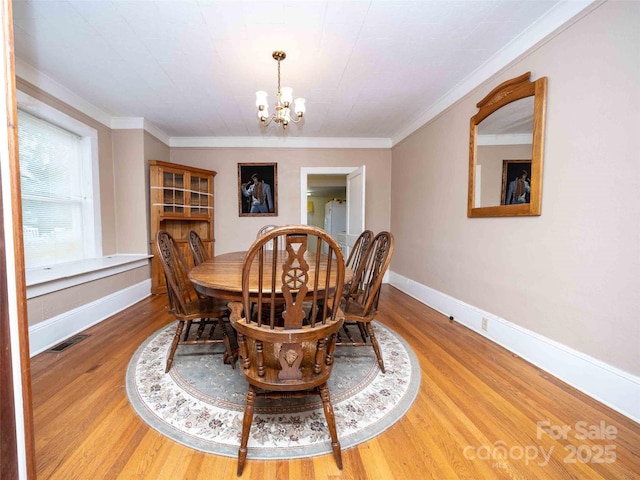 dining space featuring baseboards, ornamental molding, a notable chandelier, and wood finished floors