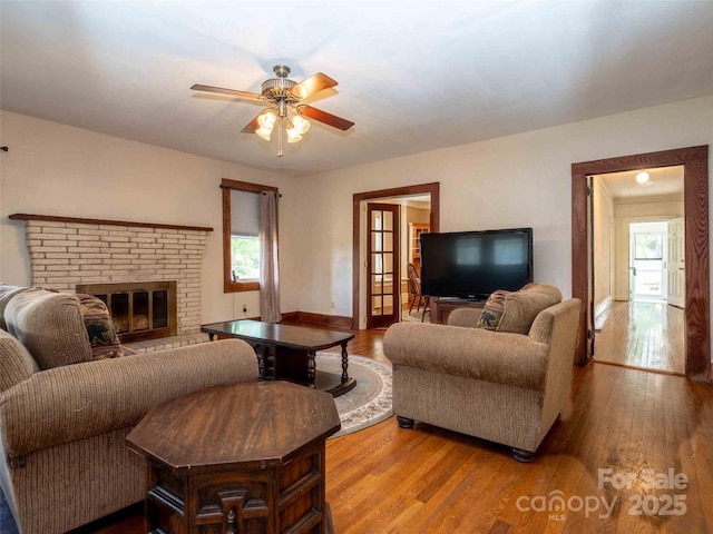 living area with plenty of natural light, light wood-style flooring, and a brick fireplace