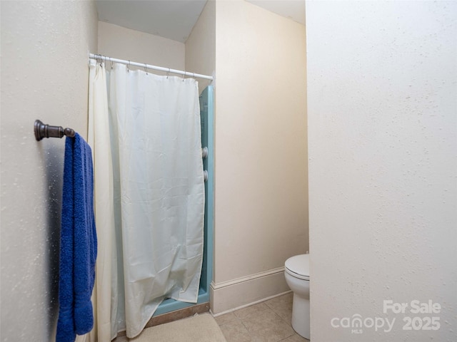 full bathroom with toilet, tile patterned flooring, baseboards, and a shower stall