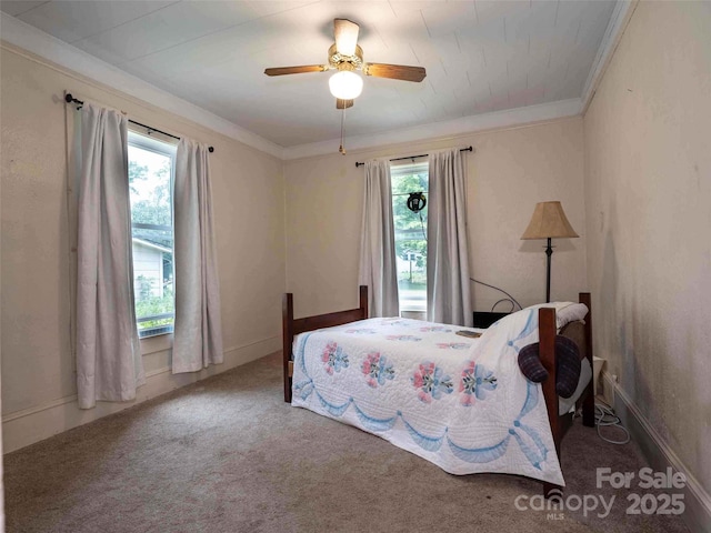 carpeted bedroom featuring ceiling fan, baseboards, and crown molding