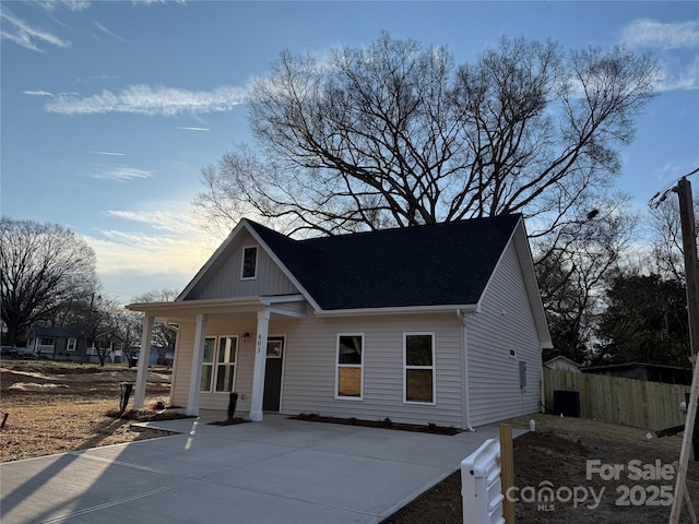 bungalow featuring covered porch, fence, and board and batten siding