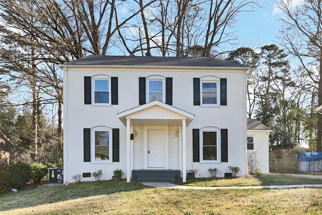 colonial-style house with a front lawn, crawl space, fence, and brick siding