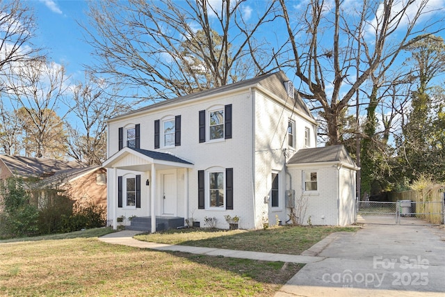 view of front facade featuring a gate, fence, a front lawn, and brick siding