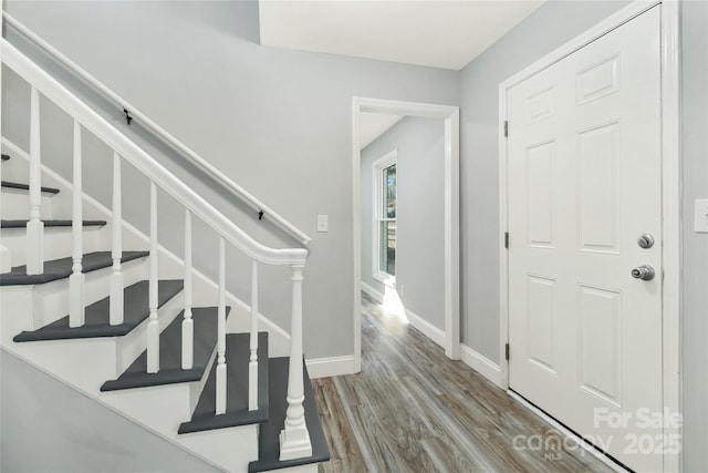 entryway with stairs, baseboards, and wood finished floors