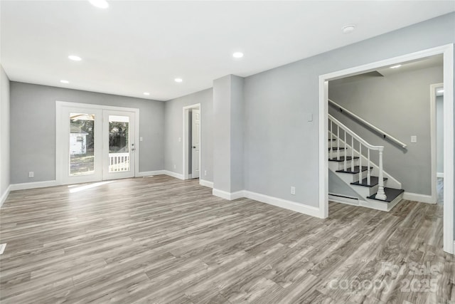 unfurnished living room with stairway, wood finished floors, and baseboards